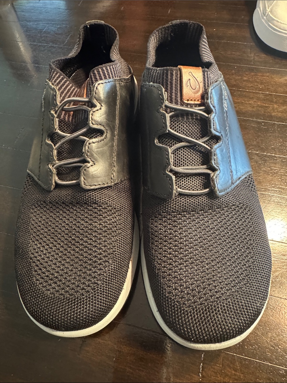 OluKai Moku-pai Men’s Knit Slip-On Sneakers in Black with black leather accent.